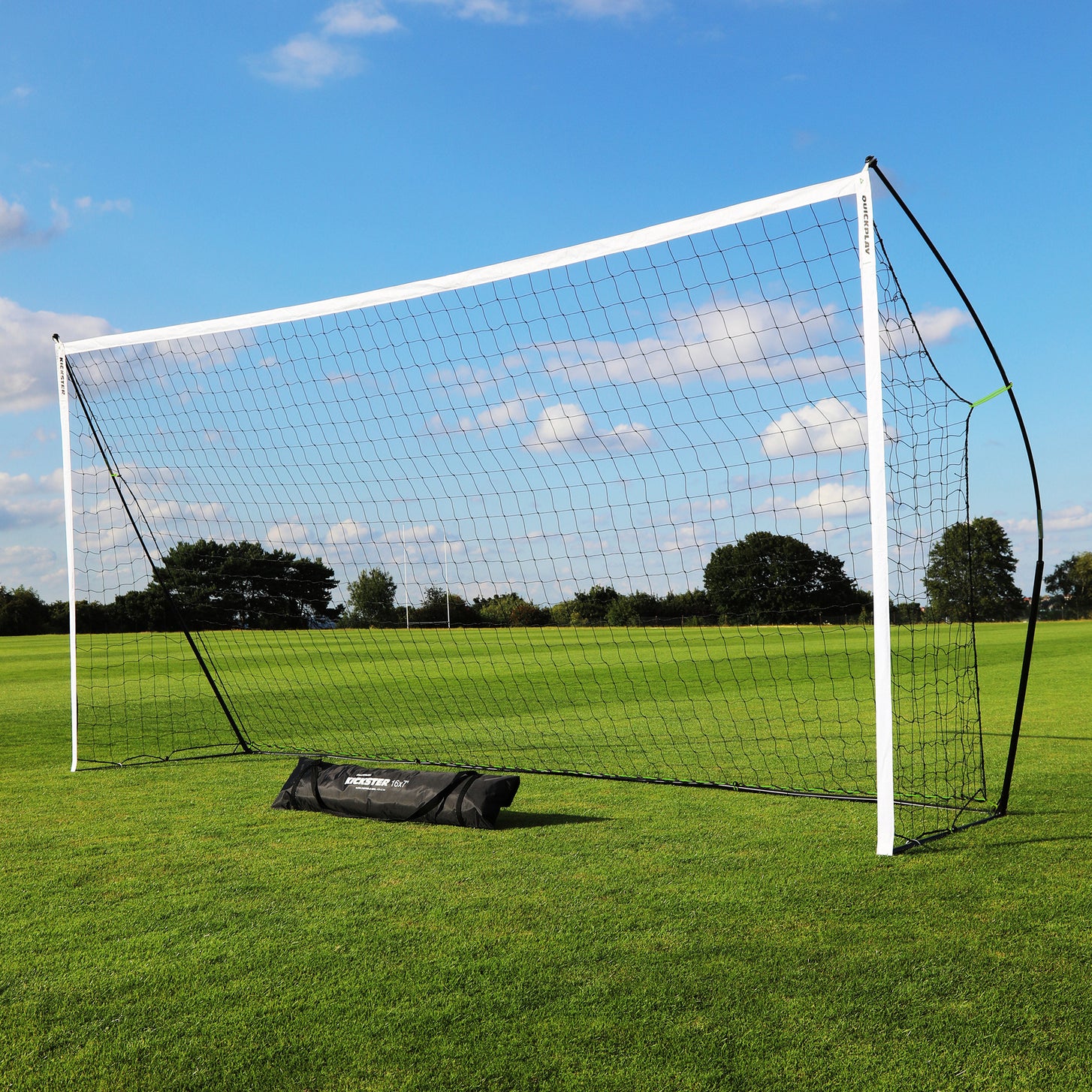 KICKSTER Tragbares Fußballtor 500 x 200 cm auf einem Rasenfeld aufgebaut, davor liegt eine schwarze KICKSTER Tasche.