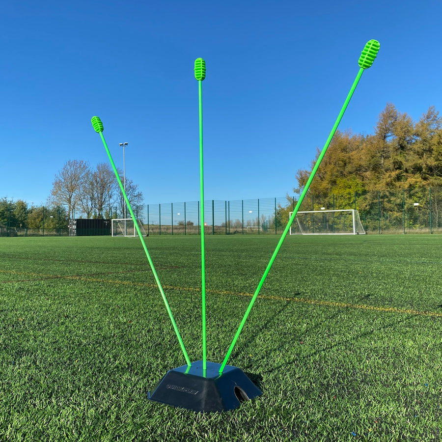Basisgewicht 2er-Set für KICKSTER, SPOT und Slalomstangen: ein Gewicht hält drei grüne Stangen in verschiedenen Winkeln auf einem Platz.
