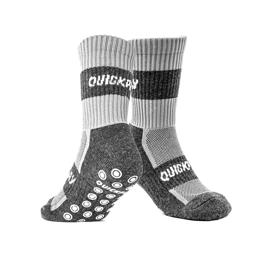 Paar QUICKPLAY Grip-Socken in Hell- und Dunkelgrau, gekreuzt, mit Blick auf die Seite und die Sohle mit weißen Grip-Noppen.