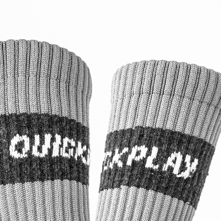 Gerippte hellgraue Bündchen zweier QUICKPLAY Grip-Socken in Nahaufnahme, mit dem dunkelgrauen QUICKPLAY Band.