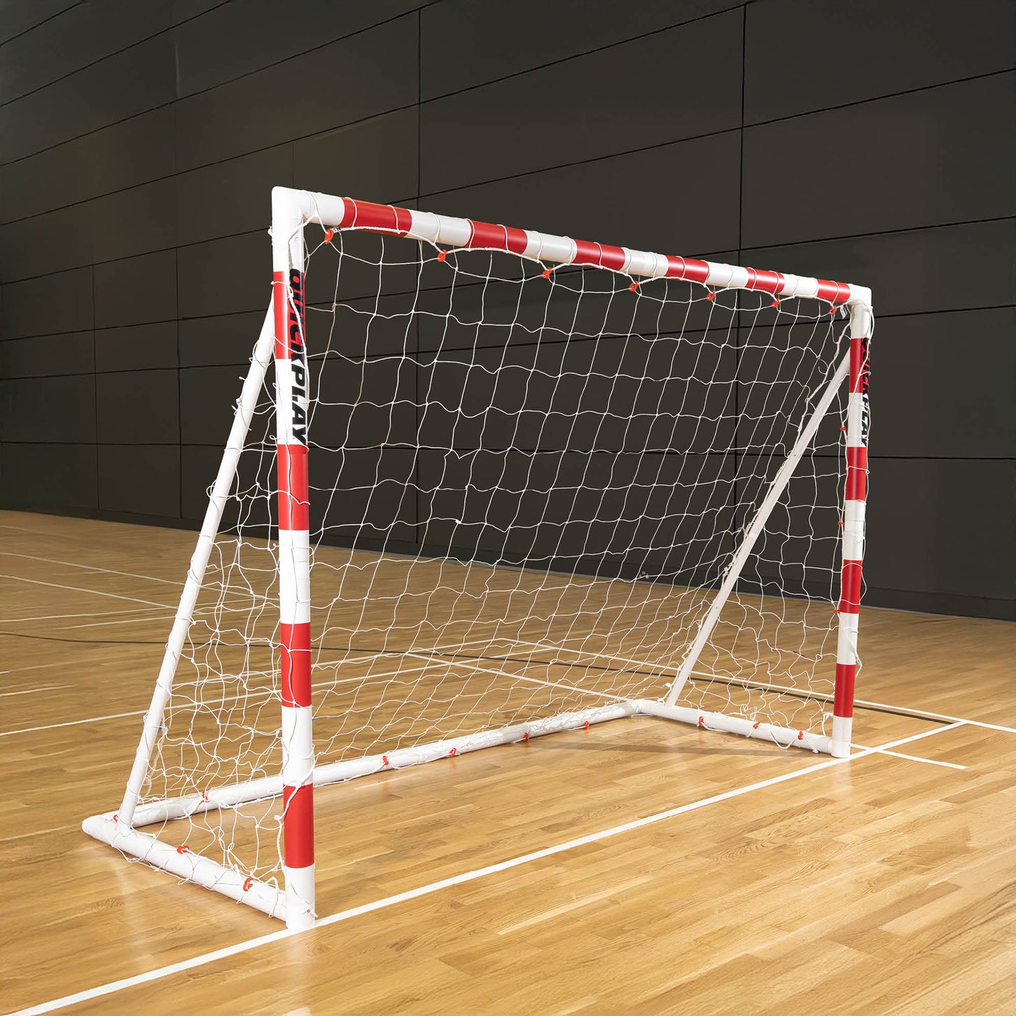 Q-FOLD Klappbares Jugend-Handballtor 240 x 170 cm mit rot-weißem Rahmen und weißem Netz, auf dem Holzboden einer Sporthalle.