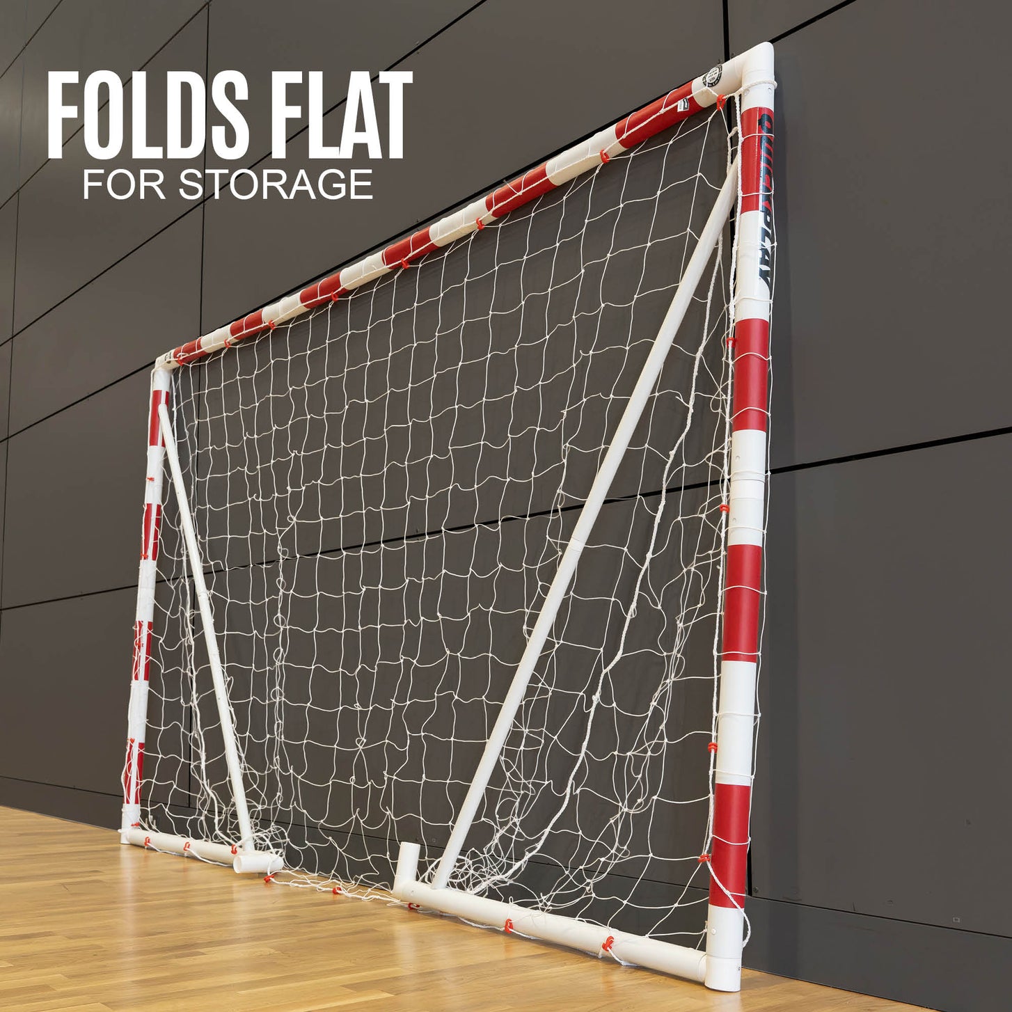 Q-FOLD Jugend-Handballtor 240 x 170 cm flach zusammengeklappt an einer Sporthallenwand, Text „folds flat for storage“.