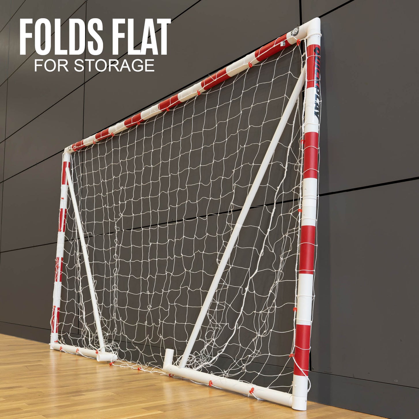 Q-FOLD Handballtor 300 x 200 cm flach zusammengeklappt an einer Sporthallenwand, mit dem Text „Folds flat for storage“.