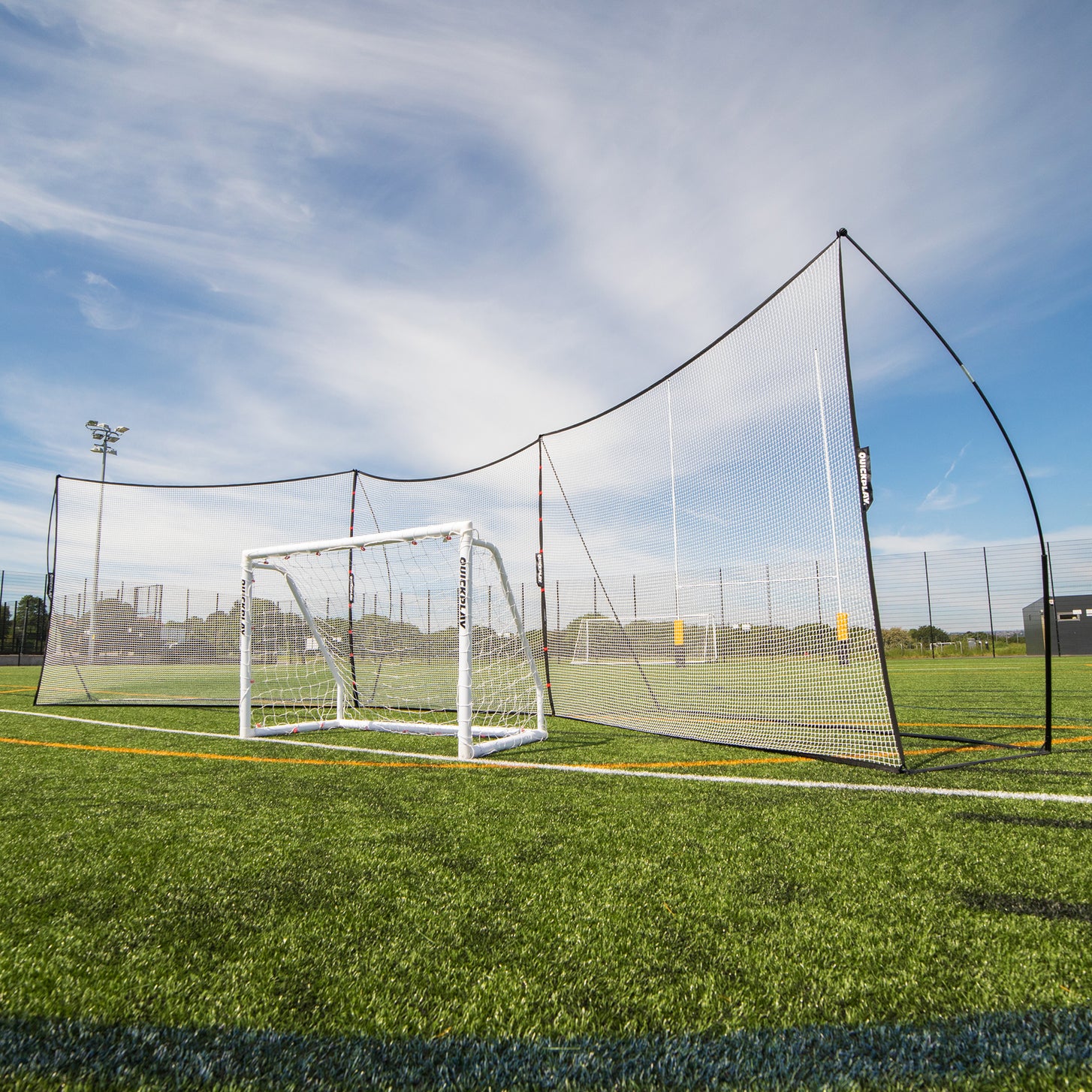 Erweiterungsnetz 240 x 270 cm verbindet zwei MEGA NETs zu einer Ballfangnetz-Reihe hinter einem weißen QUICKPLAY Tor auf einem Kunstrasenplatz.