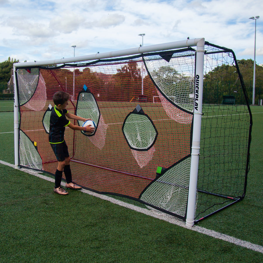 Junge legt einen Ball in eine der Fangtaschen des TARGET Torwand-Netzes 370 x 180 cm auf einem Kunstrasenplatz.