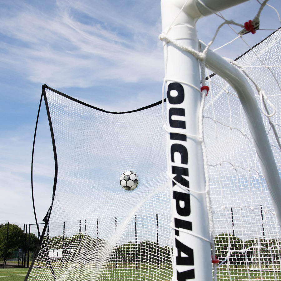 MEGA NET Ballfangnetz 370 x 270 cm fängt einen Fußball hinter einem weißen QUICKPLAY Torpfosten, von unten gesehen.
