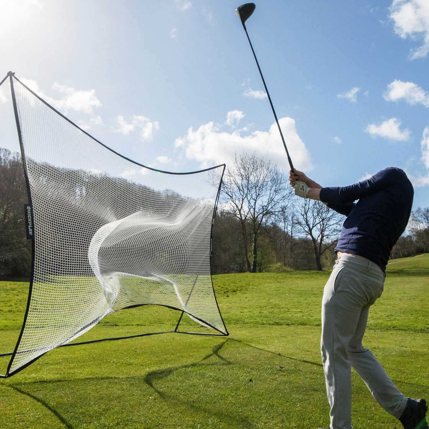 MEGA NET Ballfangnetz 370 x 270 cm auf einem Rasenfeld, ein Golfer schwingt einen Driver, nachdem er einen Ball ins Netz geschlagen hat.