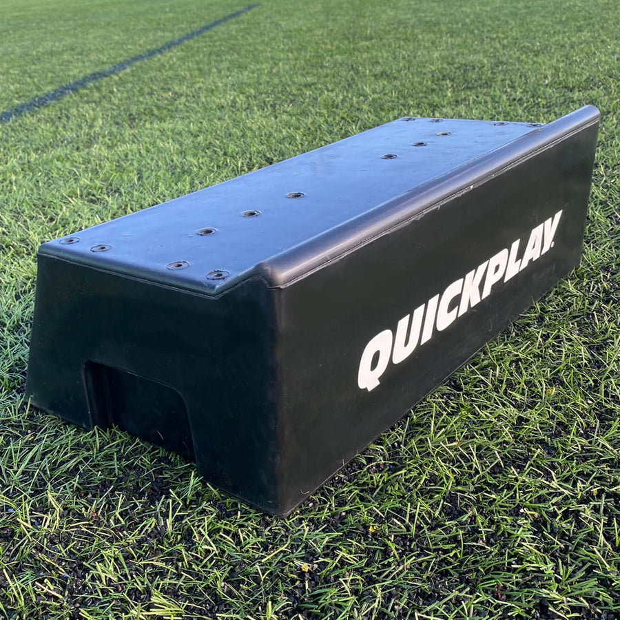 REPLAY Block Rebound-Board mit Doppelwinkel: schwarzer QUICKPLAY Block auf Kunstrasen, mit den Löchern oben und dem offenen Ende.