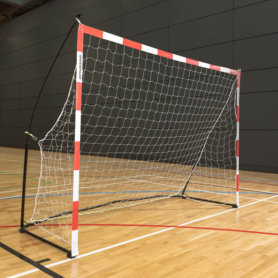 Tragbares Jugend-Handballtor 240 x 170 cm mit rot-weißen Pfosten, weißem Netz und schwarzem Rahmen, in einer Sporthalle.